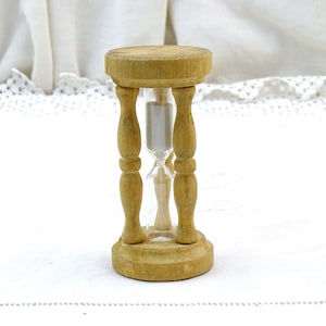 以下が含まれることがあります： 透明なガラス球を持つ小さな木製砂時計。砂時計は白い砂で満たされ、木製のベースがあります。