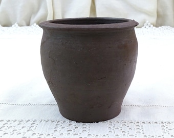 May include: A dark brown, unglazed, ceramic pot with a rounded body and a slightly flared rim.