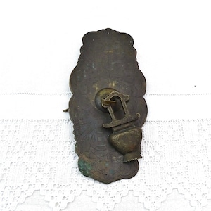 May include: Ornate brass door pull with an intricate design and a decorative vase-shaped handle.