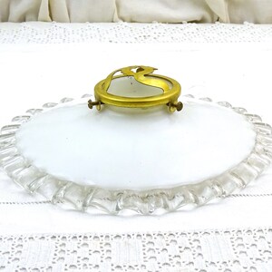 Puede incluir: Una l&aacute;mpara de techo de vidrio blanco con un borde festoneado y un anillo de lat&oacute;n con un dise&ntilde;o decorativo.