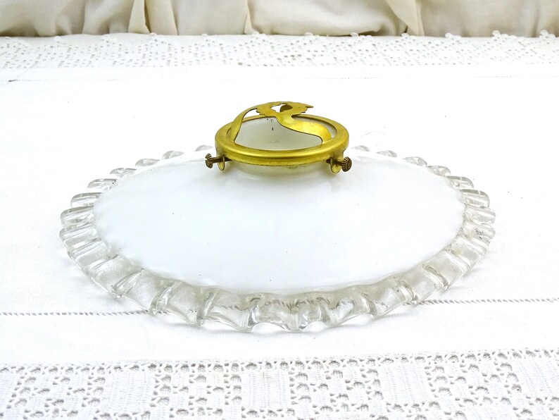 Puede incluir: Una l&aacute;mpara de techo de vidrio blanco con un borde festoneado y un anillo de lat&oacute;n con un dise&ntilde;o decorativo.