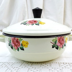Può includere: Piatto da portata in smalto bianco con coperchio a pomello nero. Il piatto è decorato con un motivo floreale di rose rosa e gialle.
