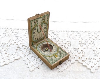 Puede incluir: Un reloj de sol de madera con una brújula y marcas de números romanos. El reloj de sol está decorado con diseños florales y tiene un esquema de color verde, amarillo y rojo.