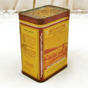 Puede incluir: Lata rectangular vintage con una combinaci&oacute;n de colores amarillo y rojo. La lata presenta texto en franc&eacute;s, incluyendo "GERMALYNE" y "REGIME NORMAL". La lata tiene un aspecto ligeramente oxidado, lo que sugiere edad y uso. El dise&ntilde;o incluye ilustraciones de personas trabajando en un campo.