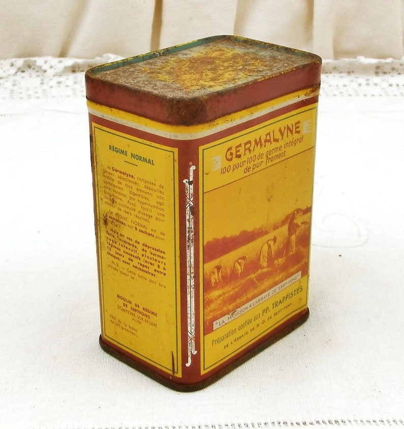 Puede incluir: Lata rectangular vintage con una combinaci&oacute;n de colores amarillo y rojo. La lata presenta texto en franc&eacute;s, incluyendo "GERMALYNE" y "REGIME NORMAL". La lata tiene un aspecto ligeramente oxidado, lo que sugiere edad y uso. El dise&ntilde;o incluye ilustraciones de personas trabajando en un campo.