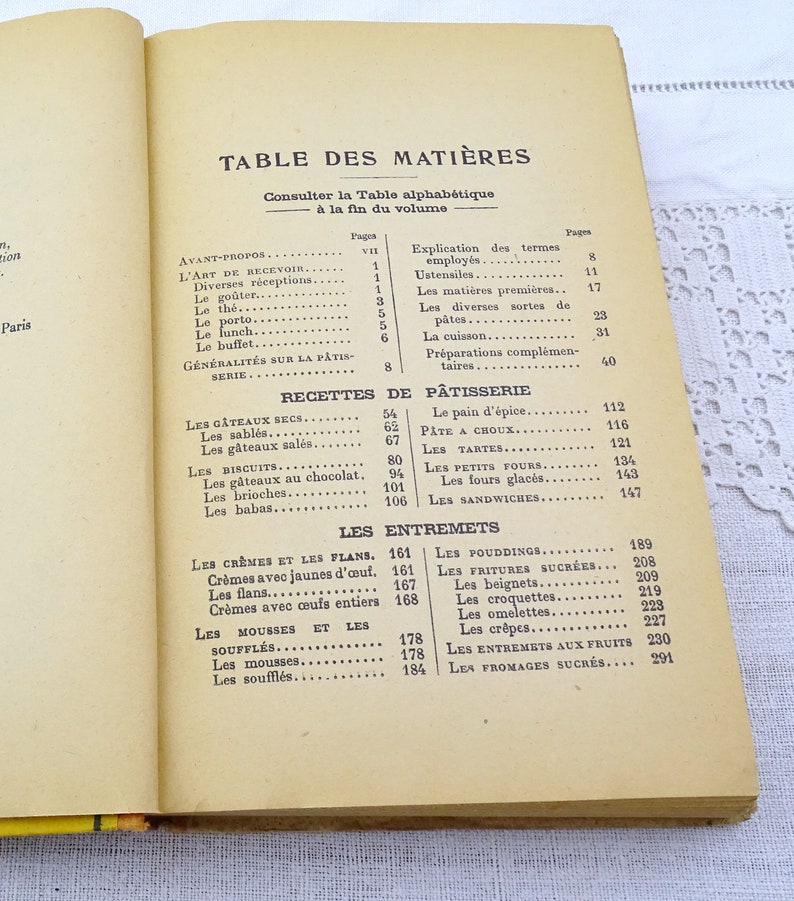 Pode incluir: Um livro de cozinha franc&ecirc;s vintage com uma capa amarela e uma tabela de conte&uacute;do listando receitas de sobremesas, bolos e doces. O livro &eacute; intitulado "Table des Mati&egrave;res" e inclui uma lista de receitas em franc&ecirc;s.