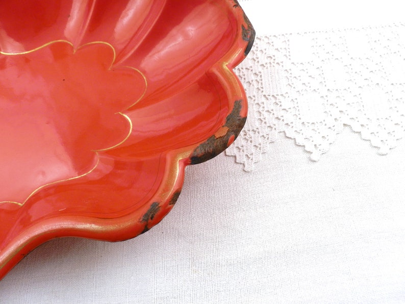 May include: A bright orange, scalloped serving dish with a gold trim. The dish is made of metal and has a vintage look.