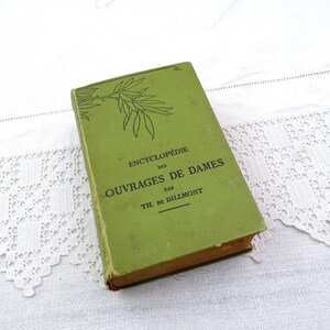 May include: A green book titled "Encyclopédie des Ouvrages de Dames" by Th. de Dillmont. The book cover features a stylised illustration of a branch with leaves.