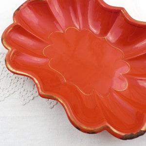 May include: A bright orange, scalloped serving dish with a gold rim and a gold design in the centre.