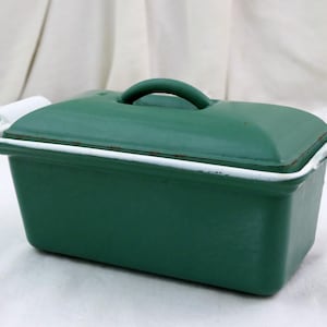 Puede incluir: Una cacerola rectangular de hierro fundido verde oscuro con tapa y asa a juego. El borde y las asas están adornados con pintura blanca. Esta cacerola vintage es ideal para hornear y cocinar.