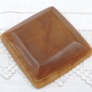 May include: A square, brown ceramic dish with a slightly raised edge. The dish has a light brown glaze with a subtle marbled effect.