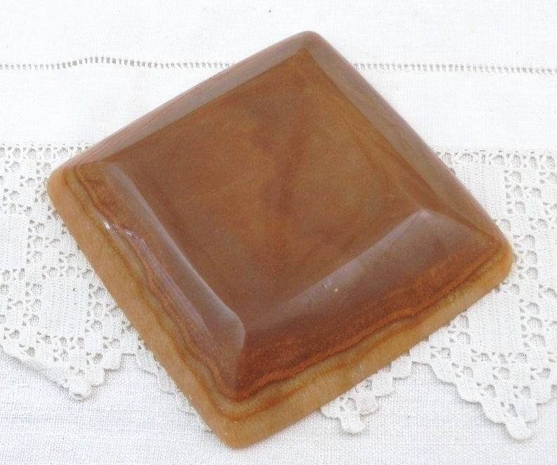 May include: A square, brown ceramic dish with a slightly raised edge. The dish has a light brown glaze with a subtle marbled effect.