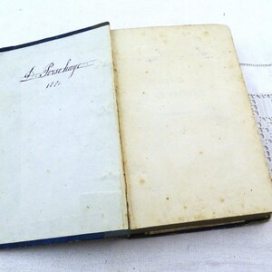 May include: An open book with a blue cover and a handwritten inscription on the first page that reads "J. Persehayre 1822".
