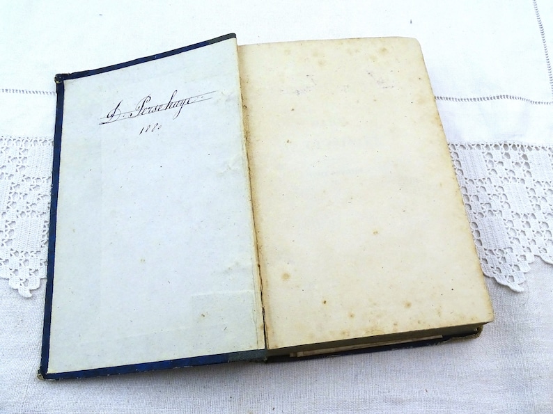 May include: An open book with a blue cover and a handwritten inscription on the first page that reads "J. Persehayre 1822".