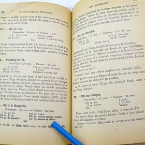 Pode incluir: Um livro de cozinha franc&ecirc;s vintage aberto em uma p&aacute;gina com instru&ccedil;&otilde;es para fazer arroz com leite. A p&aacute;gina est&aacute; amarelada pelo tempo e tem notas escritas &agrave; m&atilde;o com tinta azul.