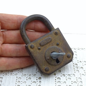 May include: A rusty metal padlock with a keyhole and the number "430" stamped on the front. The padlock is in the palm of a hand.