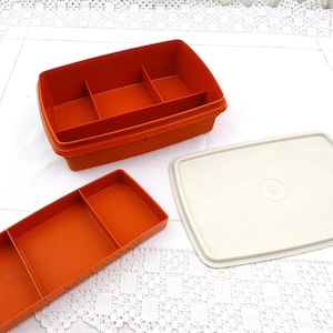 Op de afbeelding: Een oranje plastic opbergdoos met een afneembaar deksel en verdelers. De doos heeft drie compartimenten en is ideaal voor het organiseren van kleine items.