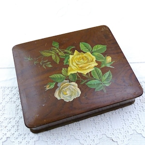 Puede incluir: Una caja de joyería cuadrada de madera con tapa con bisagras. La tapa está decorada con un diseño floral pintado con rosas amarillas y blancas, hojas verdes y tallos. La caja tiene un acabado marrón oscuro.