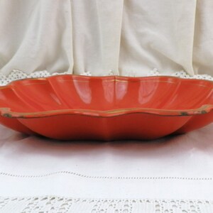 May include: A large, orange, scalloped serving bowl with a gold rim. The bowl is made of metal and has a shiny finish.