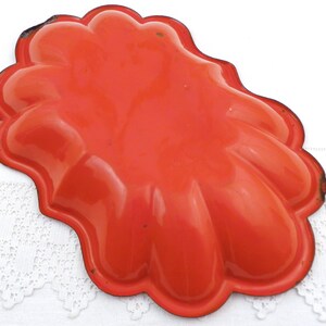 May include: Orange metal baking dish with a scalloped edge. The dish is designed to make individual servings of a dessert.