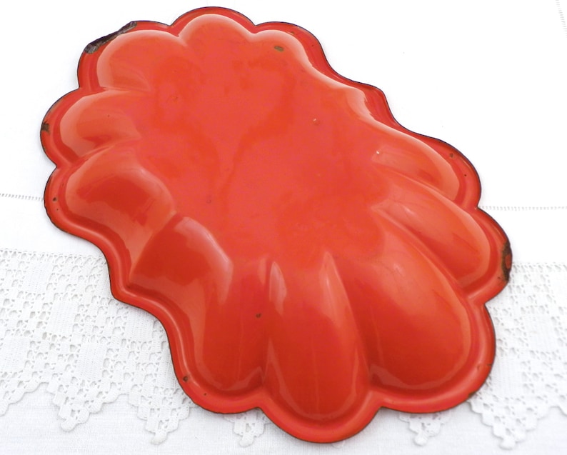 May include: Orange metal baking dish with a scalloped edge. The dish is designed to make individual servings of a dessert.