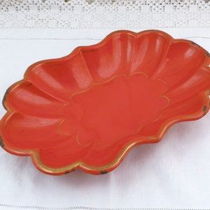 May include: An orange oval-shaped serving dish with a scalloped edge and gold trim. The dish is made of metal and has a shiny finish.