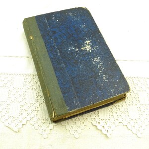 May include: A vintage blue hardback book with a green spine. The book is worn and has a faded appearance.