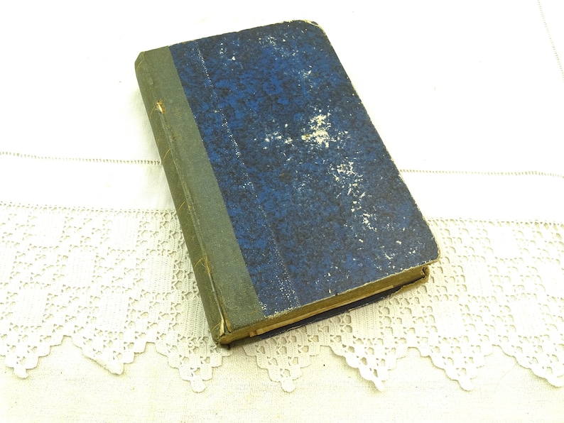 May include: A vintage blue hardback book with a green spine. The book is worn and has a faded appearance.