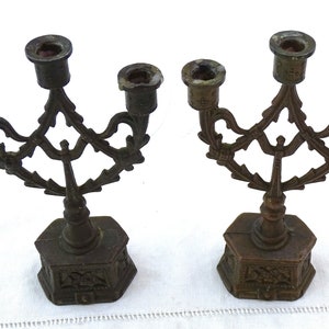 May include: Two antique bronze candelabra with ornate designs and five candle holders each.