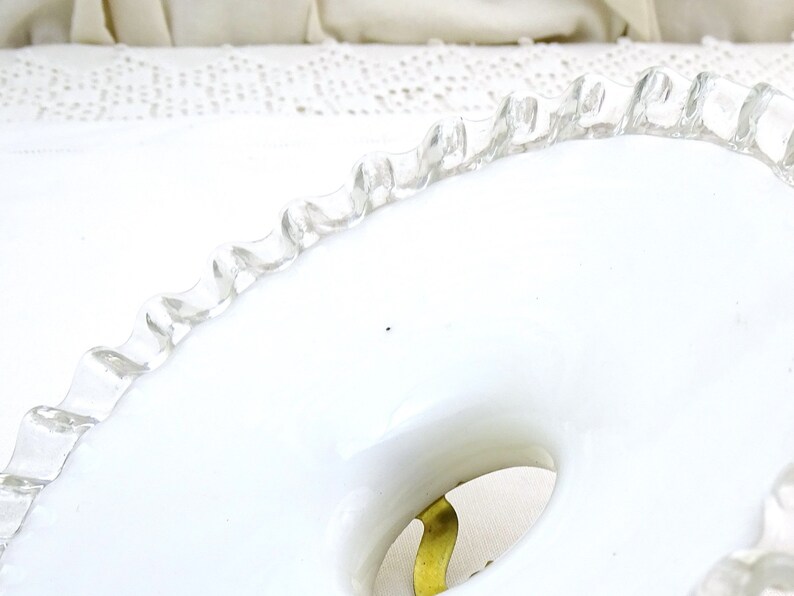 Puede incluir: Un plato de cer&aacute;mica blanco con un borde festoneado. El plato tiene un agujero en el centro y un dise&ntilde;o dorado alrededor del agujero.