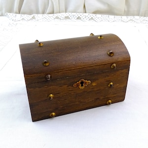 May include: A small wooden treasure chest with a hinged lid and a brass lock. The chest is decorated with brass studs and has a rounded top.