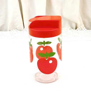 May include: A red and clear glass jar with a red lid and a red apple design. The jar has a pour spout and is perfect for storing sugar, spices, or other small items.