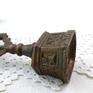 May include: A pair of antique brass candle holders with ornate designs. The holders are in the shape of a cross with a floral motif.