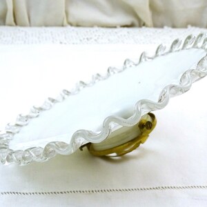 Puede incluir: Plato de vidrio blanco con borde festoneado y borde de vidrio transparente. El plato tiene un accesorio de metal de lat&oacute;n en la parte inferior.