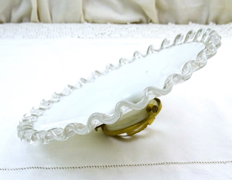 Puede incluir: Plato de vidrio blanco con borde festoneado y borde de vidrio transparente. El plato tiene un accesorio de metal de lat&oacute;n en la parte inferior.