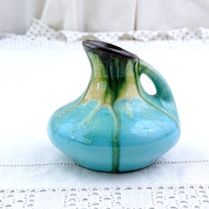 Peut inclure: Un petit pichet en céramique bleu turquoise avec un glaçage vert et brun. Le pichet a un corps arrondi et une seule anse.