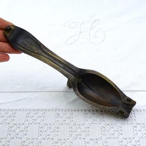May include: A vintage brass spoon with a long handle and a deep bowl. The spoon is tarnished and has a rustic look.