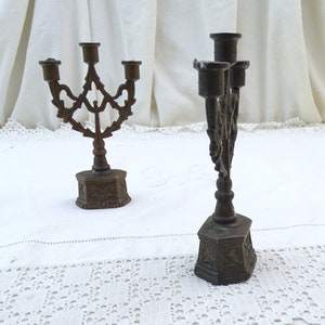 May include: Two ornate metal candle holders with a traditional design. The candle holders are made of a dark metal and have a detailed, intricate design.