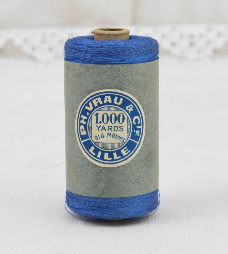 May include: A spool of blue thread with a label that reads "Ph. Vrau & Cie. 1,000 Yards 914 Metres Lille."