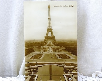 May include: Vintage sepia toned postcard featuring a black and white photo of the Eiffel Tower in Paris, France. The postcard has the text "50. PARIS - La Tour Eiffel" printed on it.