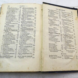 May include: An open book with yellowed pages and a blue cover. The book is titled "Table" and "Des Matieres" and contains a list of French culinary dishes and ingredients.