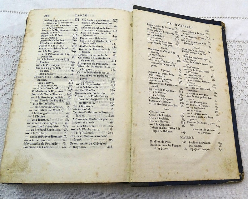 May include: An open book with yellowed pages and a blue cover. The book is titled "Table" and "Des Matieres" and contains a list of French culinary dishes and ingredients.