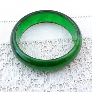 Puede incluir: Un brazalete de plástico verde. El brazalete es liso y brillante.