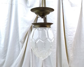 May include: A vintage ceiling light fixture with a clear glass shade featuring a geometric pattern. The fixture has a brass finish and a simple design.