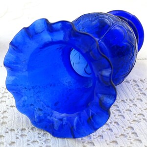 May include: A cobalt blue glass vase with a ruffled rim and a textured design. The vase is empty and appears to be vintage.