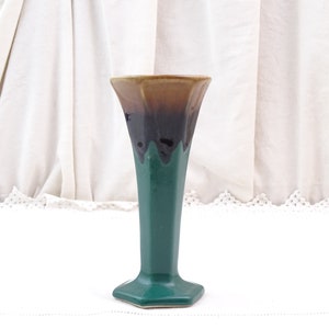 Könnte beinhalten: Eine grüne und braune Keramikvase mit sechseckigem Sockel. Die Vase hat eine ausgestellte Oberseite und eine glatte, glänzende Oberfläche.