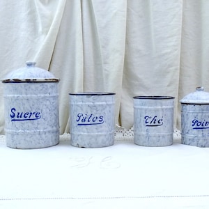 Op de afbeelding: Set van vier vintage emaille kannen met blauw-witte gespikkelde verf. De kannen zijn gelabeld met "Sucre", "Pâtes", "Thé" en "Poivre".
