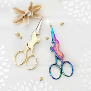 May include: Two pairs of unicorn-shaped scissors. One pair is gold and the other is iridescent.