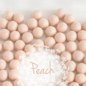 May include: A large group of peach-coloured felt balls arranged in a circle on a white surface. The text "Peach" is written in white on a white floral background.