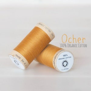 May include: Two spools of Ocher 100% organic cotton thread. The spools are made of cardboard and have a white label with black text.